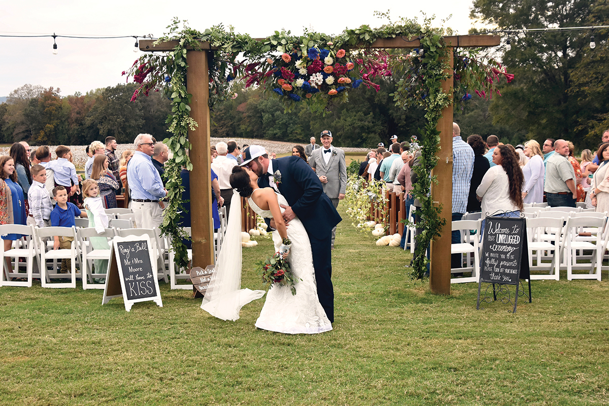 Jordan + Jordan Moore wedding, couple kissing in front of arch cotton field