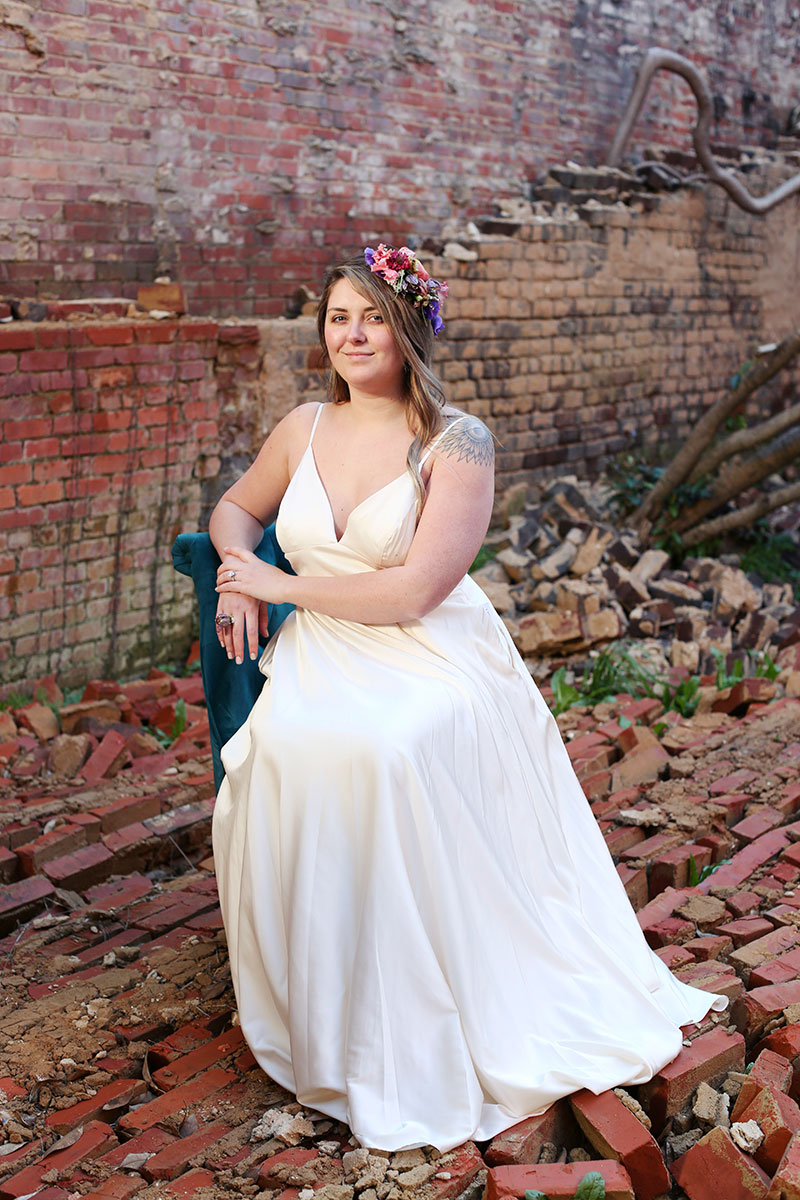 modern bride with fresh flower head piece sitting on chair around old building
