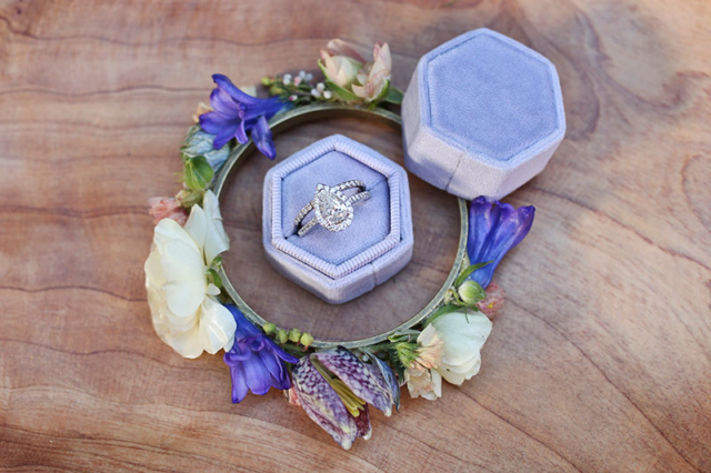 gorgeous wedding band in light purple velvet ring box surrounded by fresh flower bracelet