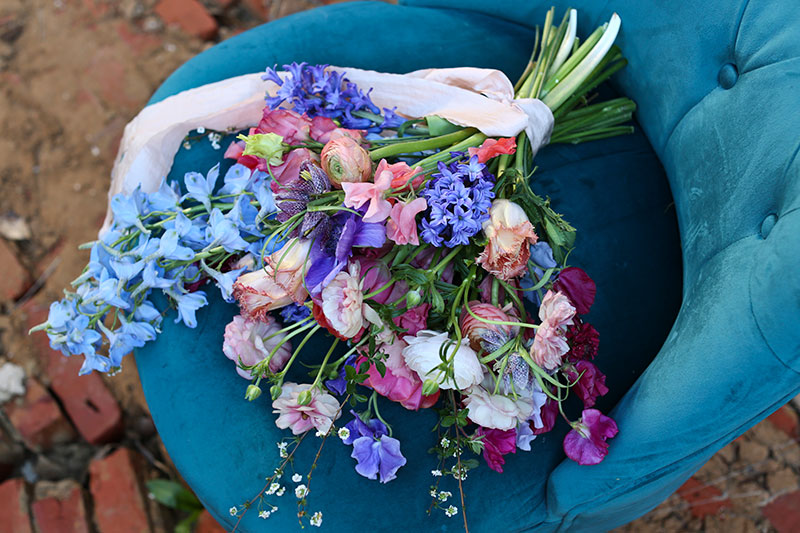 gorgeous fresh wedding flowers bouquet on turquoise velvet armchair