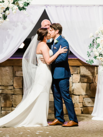married couple kissing during ceremony on church stage