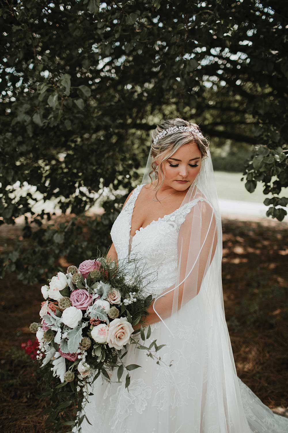 beautiful bride looking down holding bouquet dusty rose