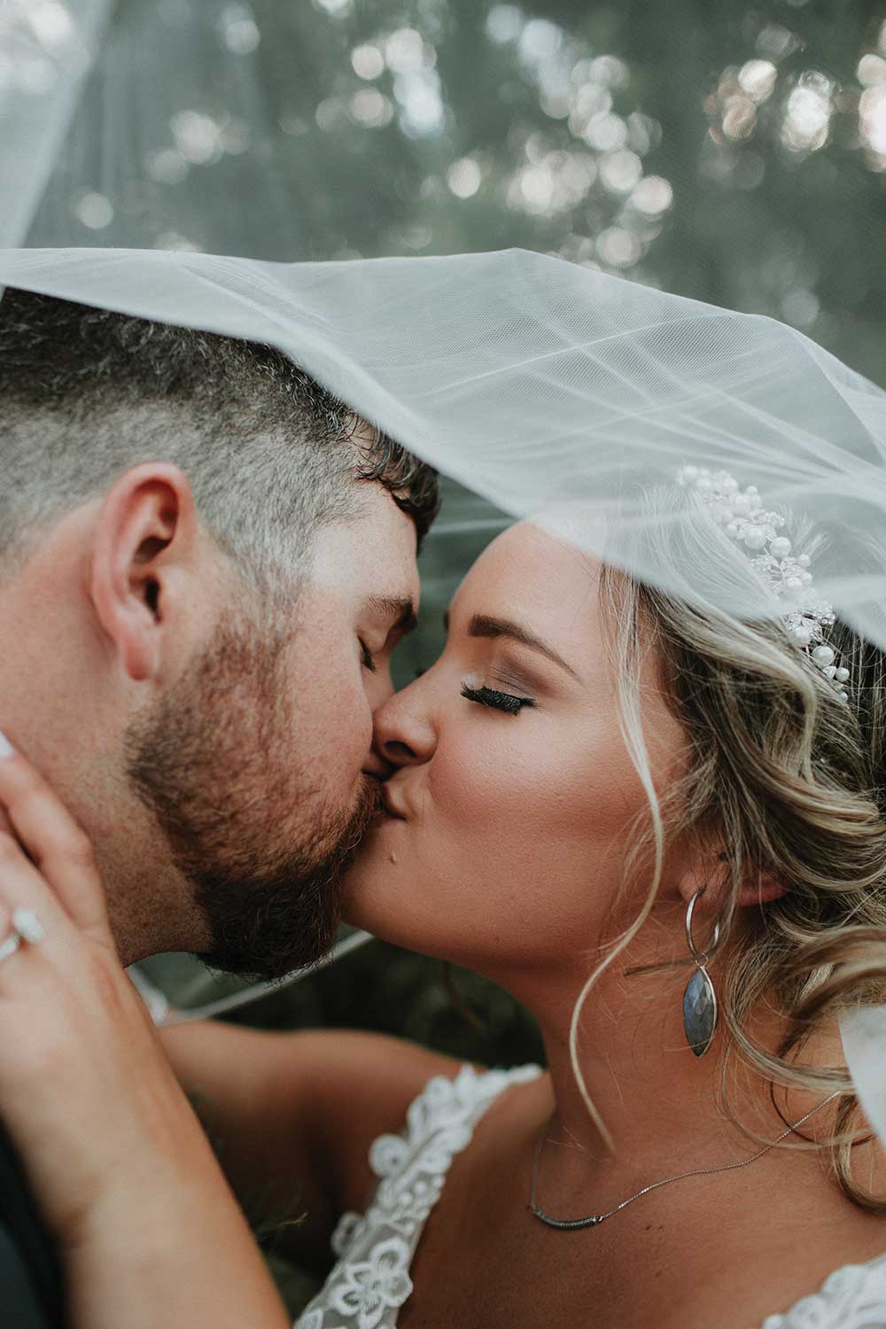 closeup of married couple kissing under flowy veil