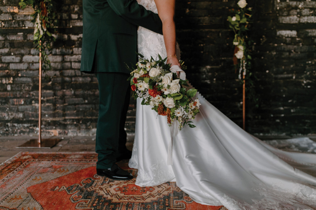 closeup bride and groom vintage emerald colors wedding bouquet with orange accent