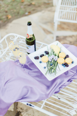 lemon and lavender macarons on purple fabric with champagne at wedding