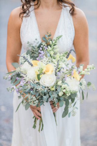 closeup bride holding wedding bouquet with yellow, light green and lavender colors
