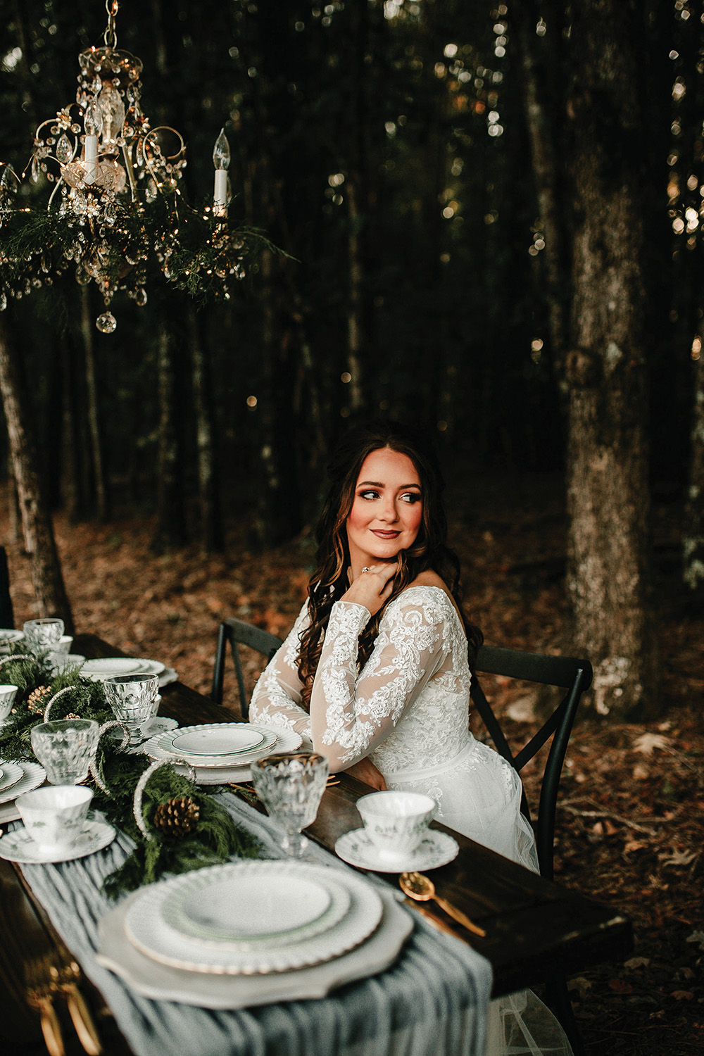 winter wedding outdoors tablescape with bride sitting under chandelier