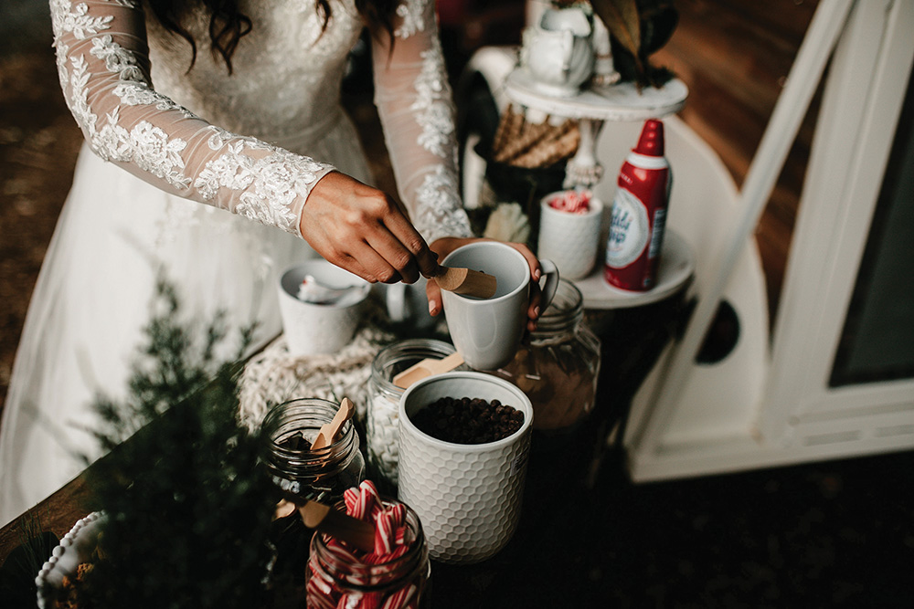 winter wedding bride at hot chocolate bar fixing a cup